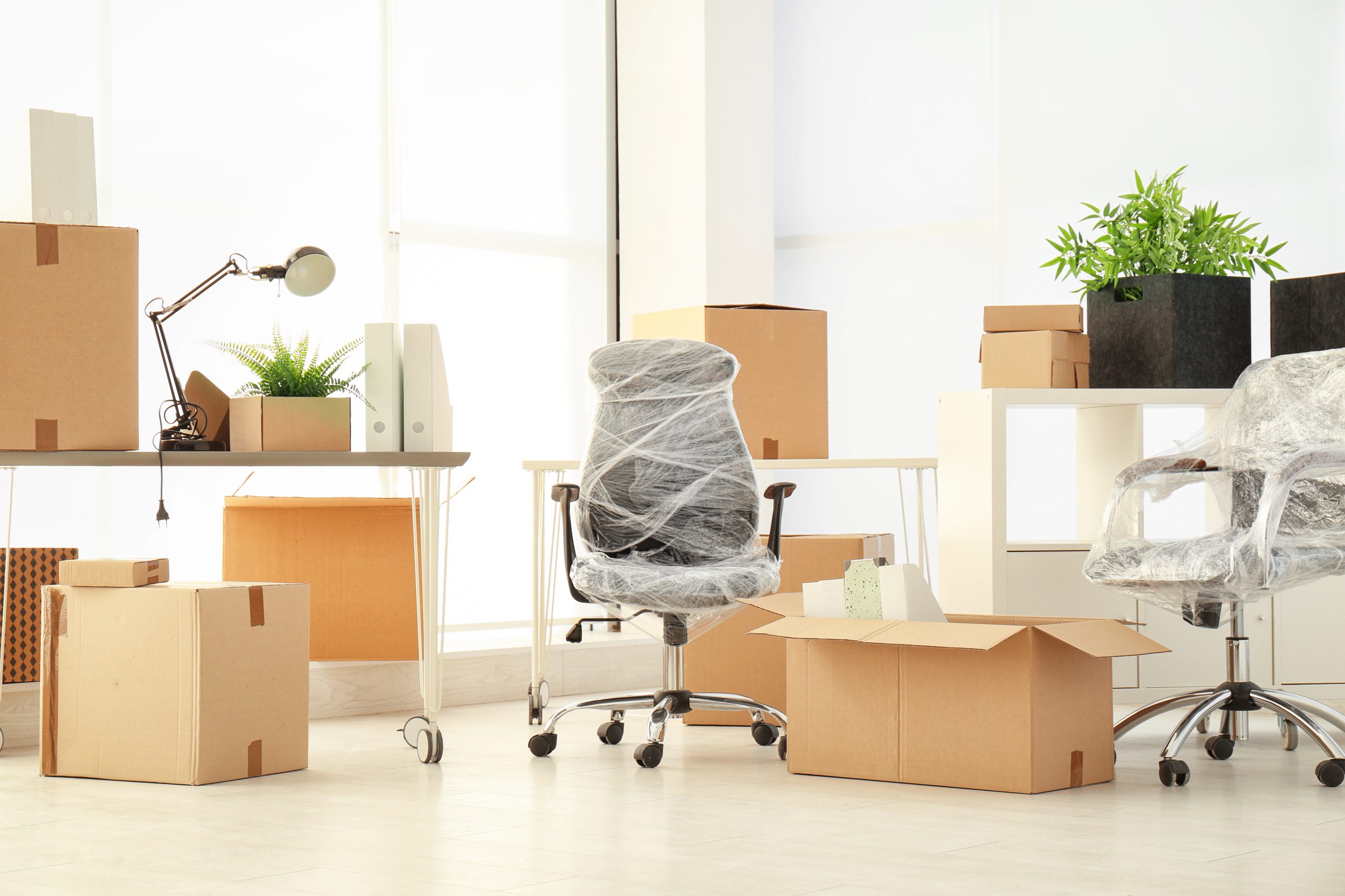 Büro mit Umzugskartons und eingewickelten Stühlen